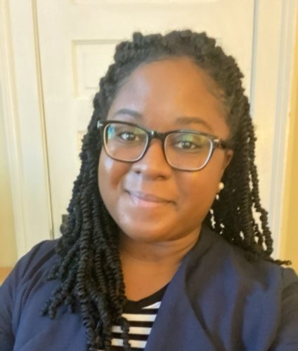 Jessica Cannady head shot: Black woman with long twists. Wearing glasses, a navy blue blazer, and black and white striped shirt.